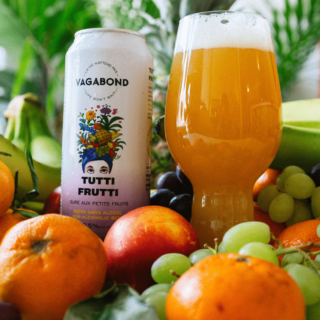 Canette de bière sans alcool Vagabond Tutti Frutti avec un verre et des fruits qui l'entoure