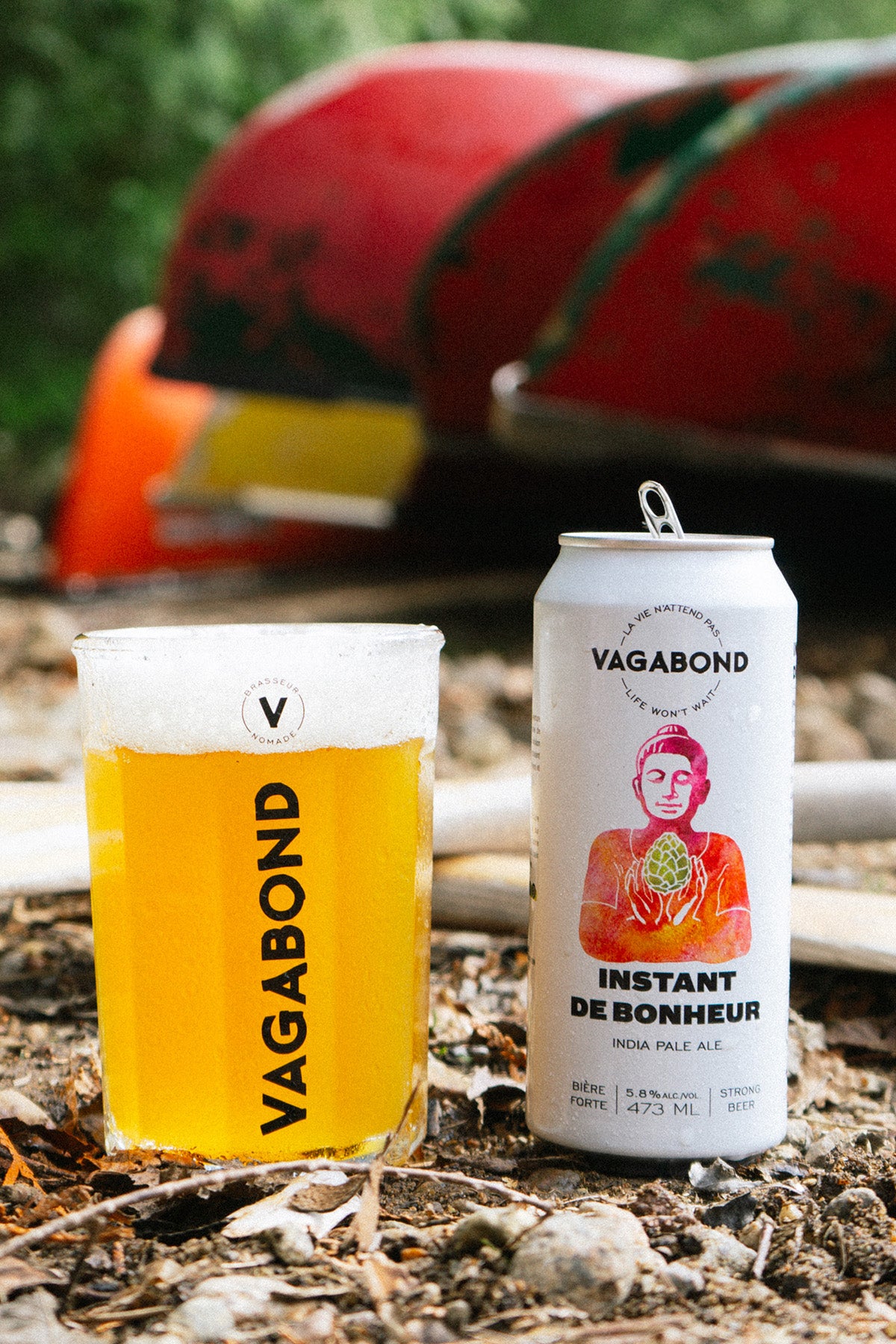 Bière Vagabond Instant de Bonheur – India Pale Ale à 5.8%, servie dans un verre et une canette posés sur le sol forestier à côté d’un canoë, évoquant la détente, la nature et la sérénité d’un moment en plein air.